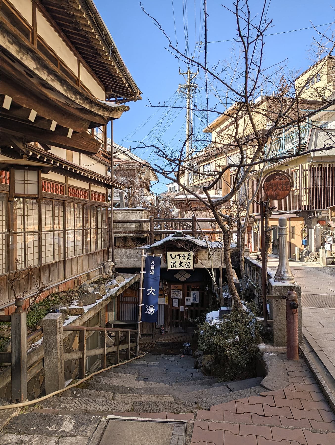 The narrow streets of an onsen town in winter, traditional wooden buildings and the entrance to a public bathhouse