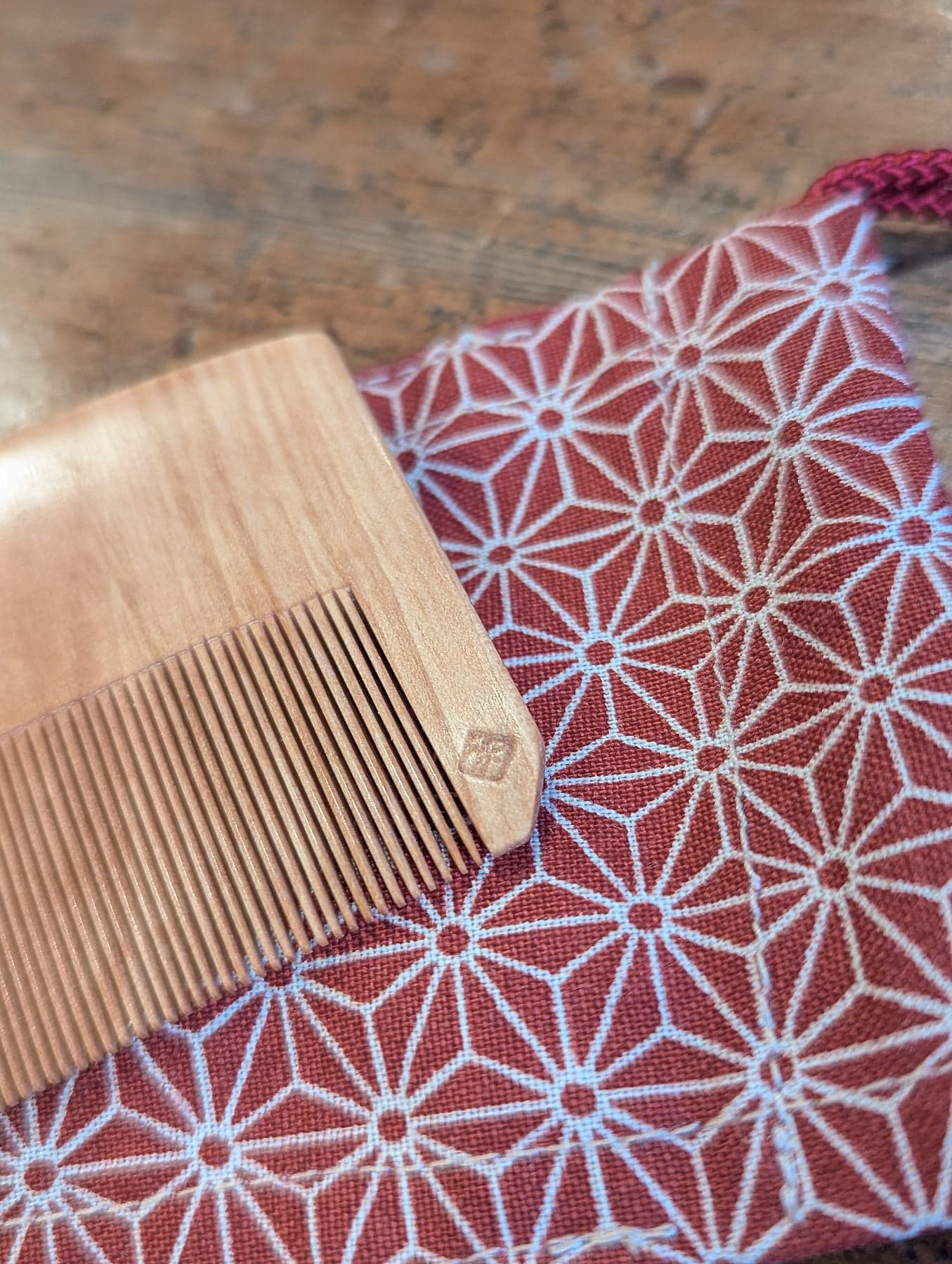 Close-up of the craftsman’s stamp pressed into the minebari wood, with the asanoha pouch behind