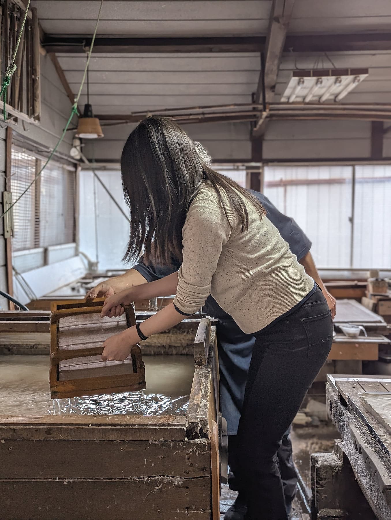 Dipping a wooden sugeta frame into the vat of mulberry pulp at the Shinshu Matsuzaki workshop, a traditional Japanese washi paper atelier in Nagano