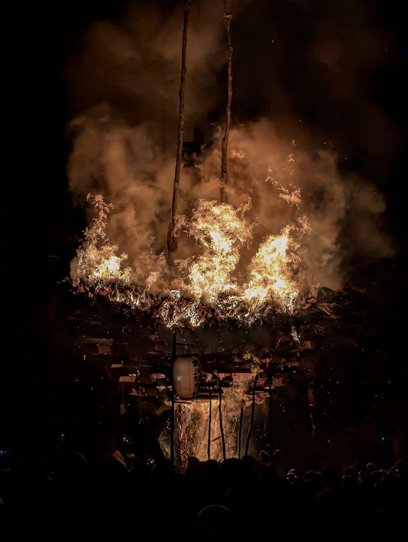 The shaden fully engulfed in flames at the Nozawa Onsen Dosojin Matsuri, timbers glowing white-hot as the structure begins to collapse