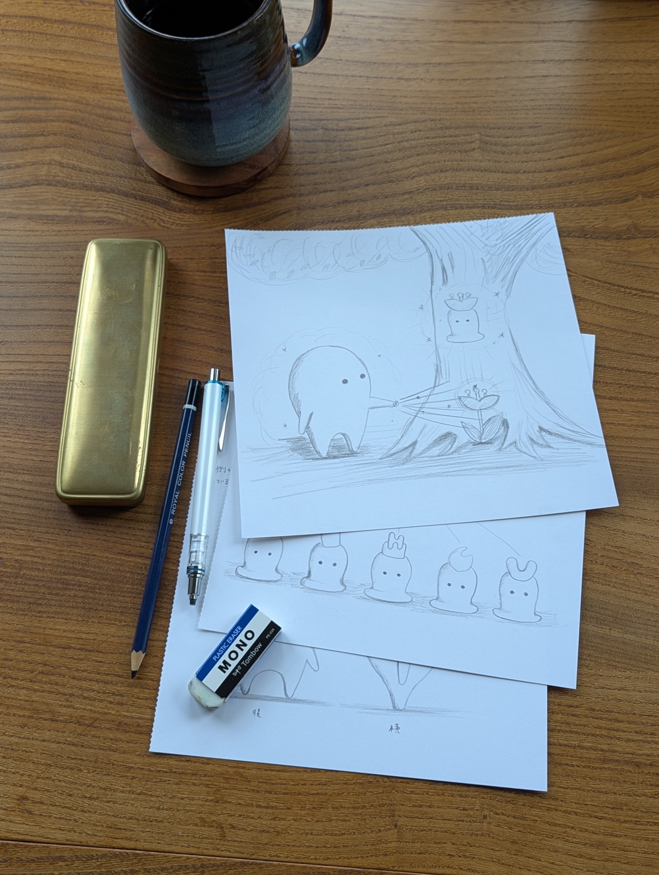 Pencil sketches of AUWA character scenes laid out on a wooden desk with a MONO eraser, mechanical pencil, and brass pencil case