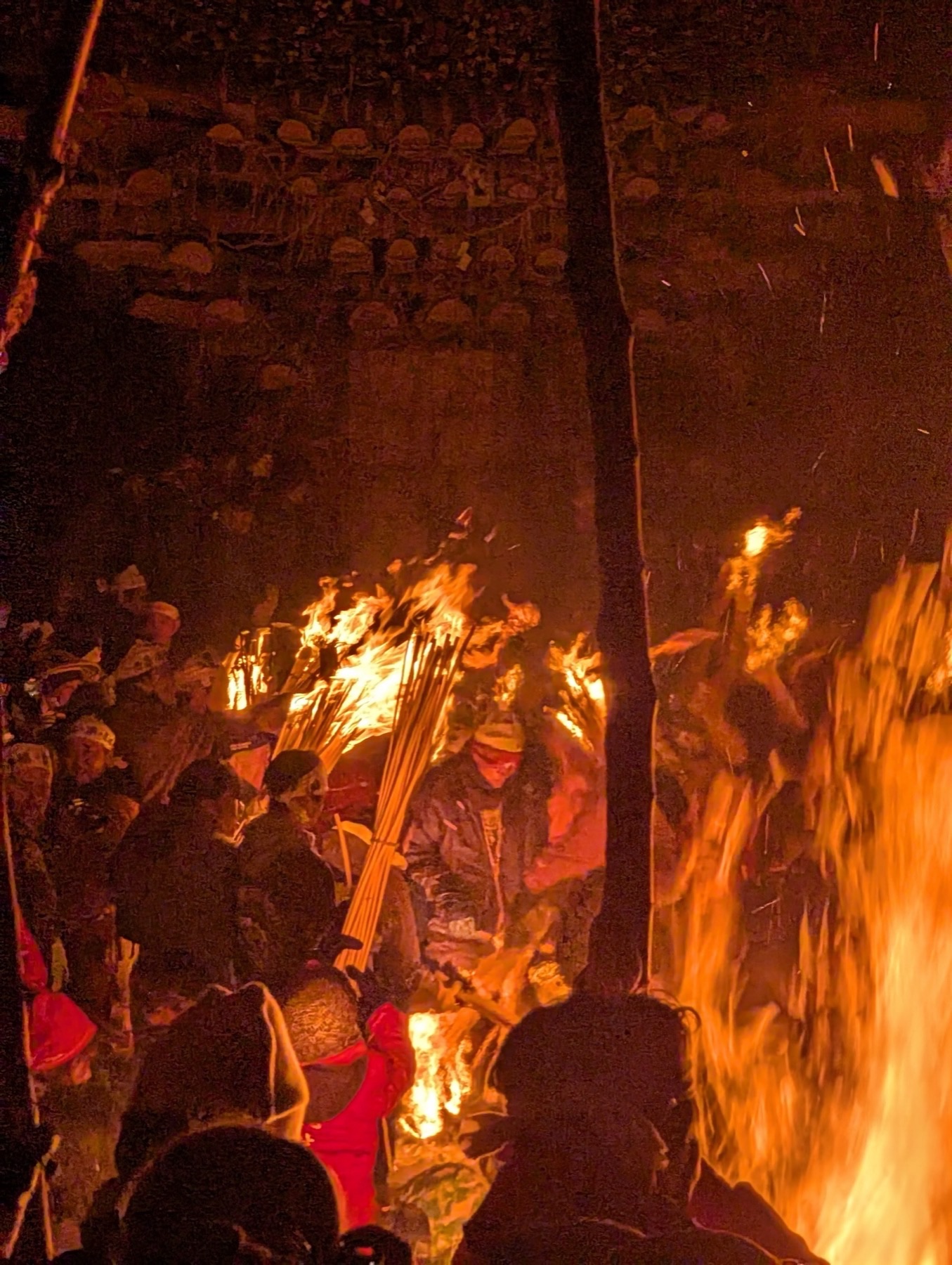 Men carrying burning straw torches press toward the base of the wooden shaden at Nozawa Onsen's Dosojin Matsuri