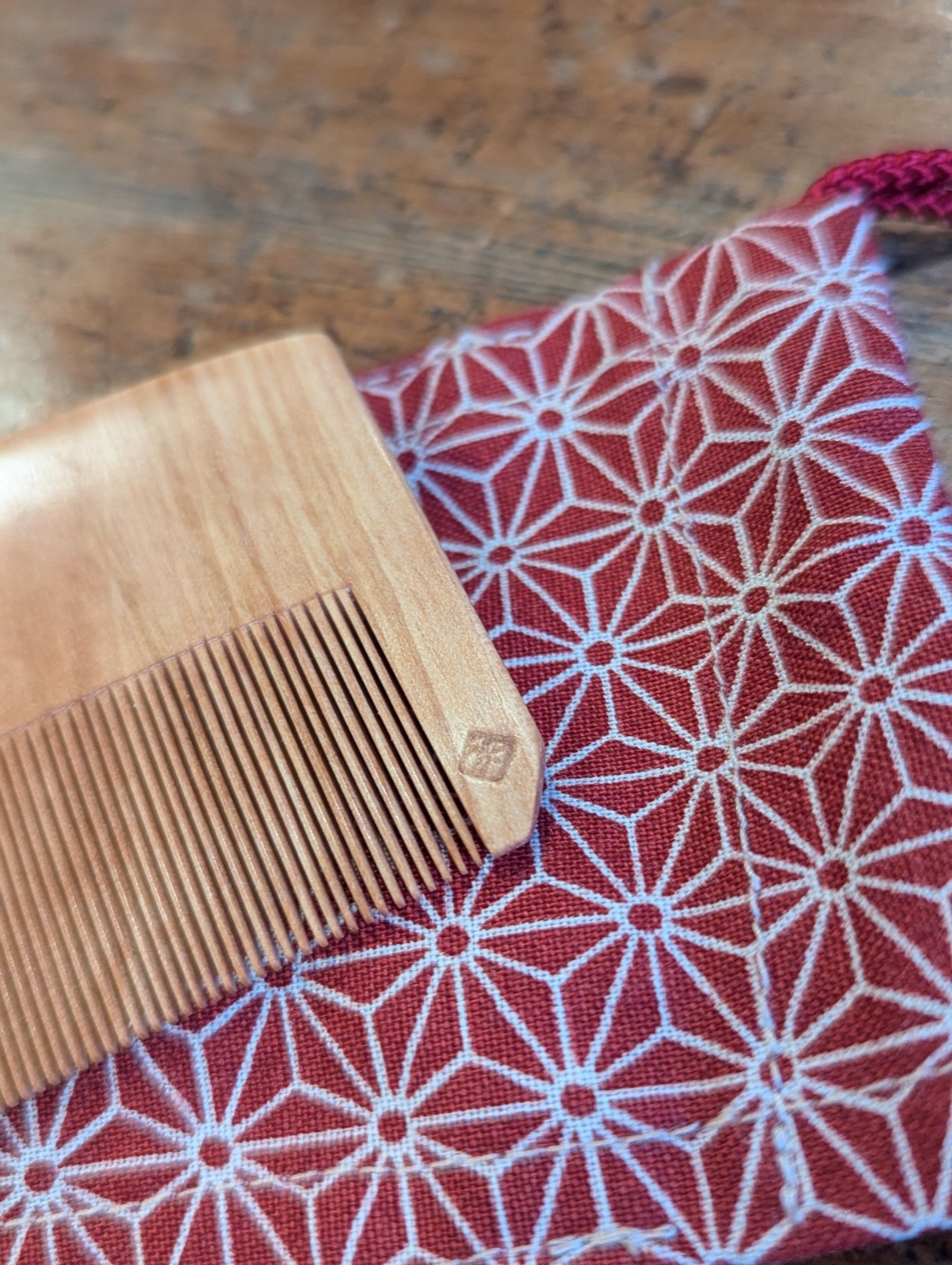 Close-up of the craftsman’s stamp pressed into the minebari wood, with the asanoha pouch behind